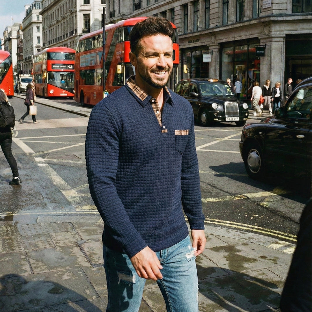 Man walking on a city street with red double-decker buses in the background