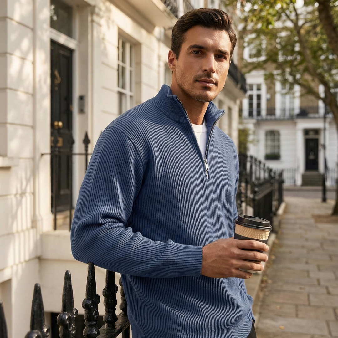 Man in a blue sweater holding a coffee cup on a city street.